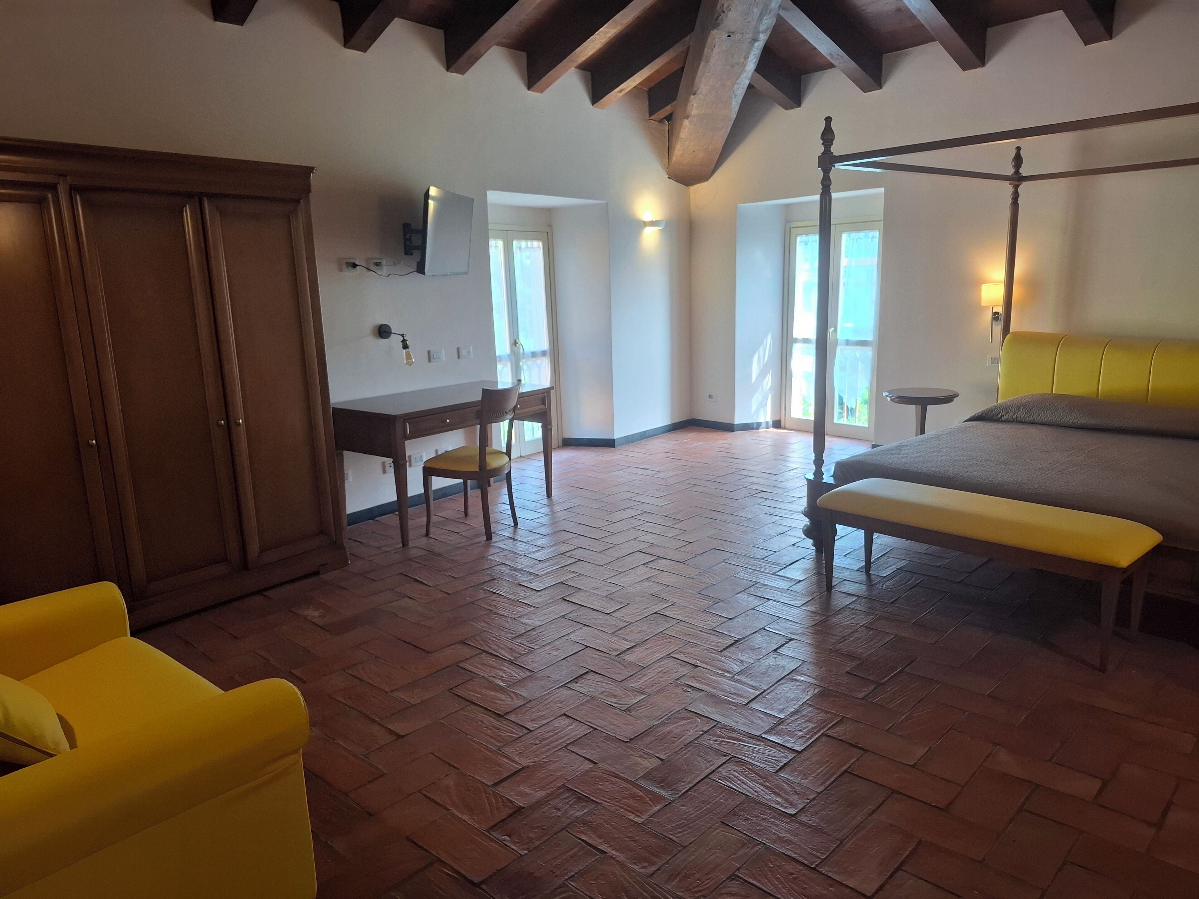 Un dormitorio con piso de madera, una cama, un escritorio, una silla y un armario.
