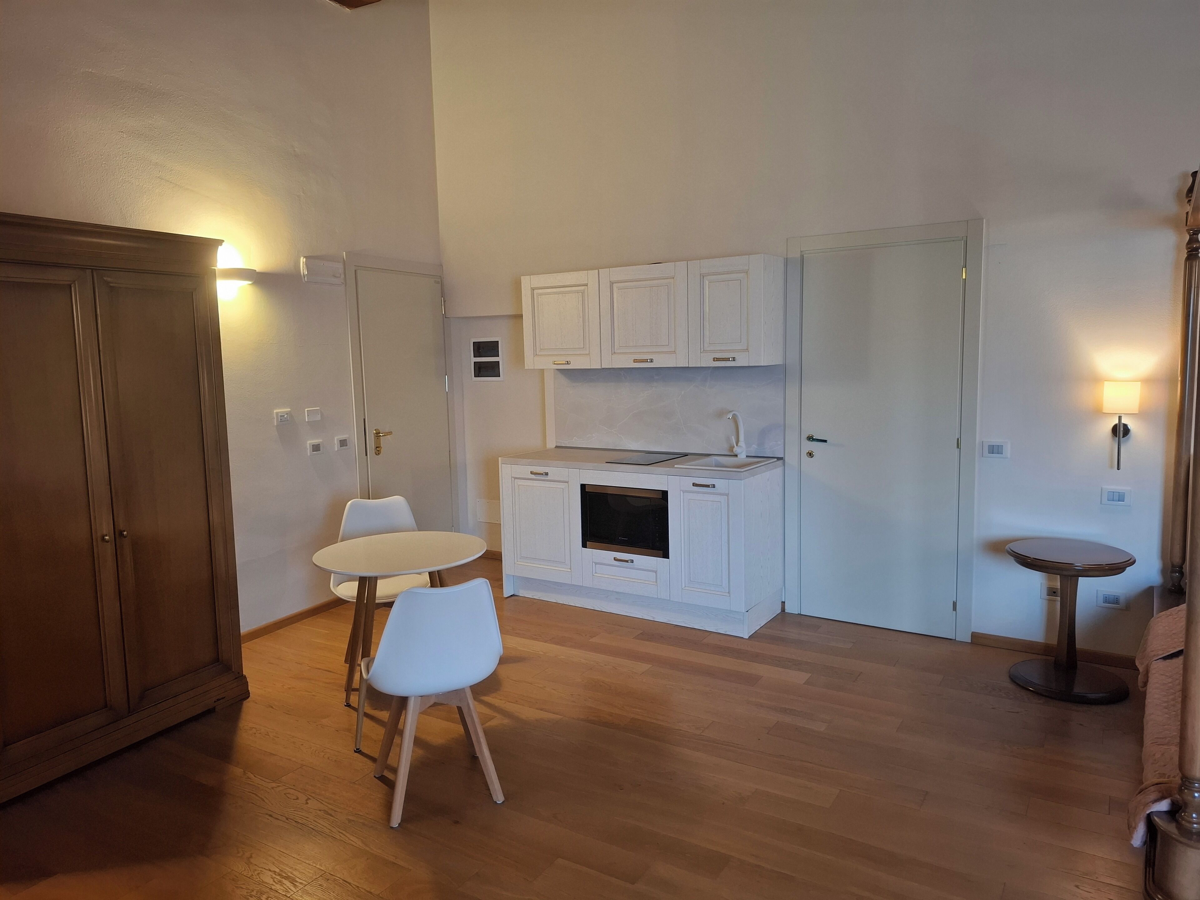 A compact kitchen with white cabinets, a small dining table, and a round side table.