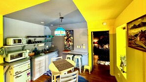 A compact kitchen with modern appliances, a dining area with stools, and a cozy seating arrangement. - Disco Den on Toad Road (Plainfield)