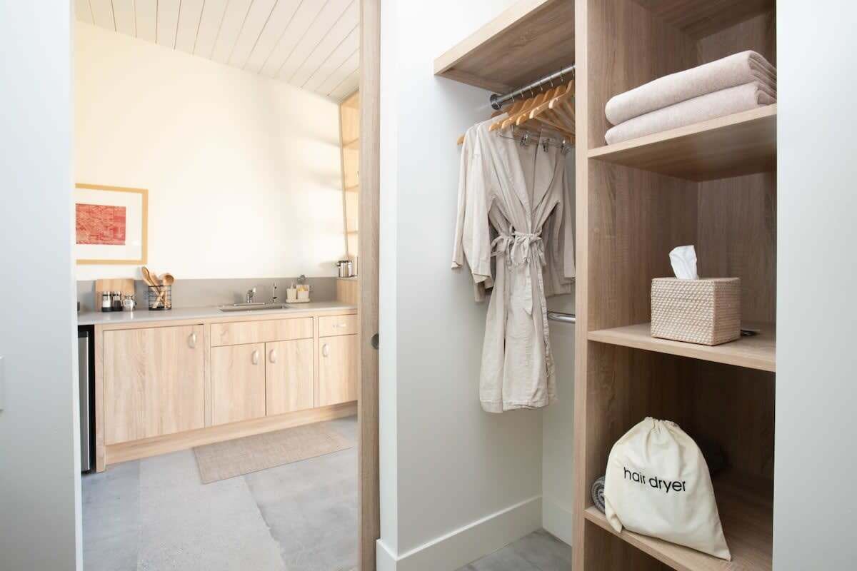 Een moderne badkamer met een houten wastafelmeubel, een handdoekhouder en een tas voor een haardroger.