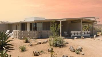 A modern house with a covered porch, desert landscaping, and a clear sky.