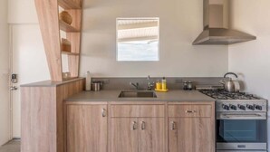 A modern kitchen with wooden cabinets, a stainless steel stove, and a window above the sink.