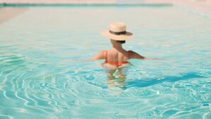 A swimming pool with clear water, a person in the water, and a clear sky.