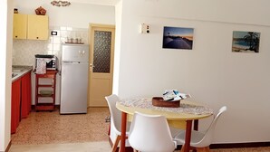 Une cuisine compacte équipée d’un réfrigérateur, d’un four à micro-ondes et d’une petite table à manger avec des chaises.
