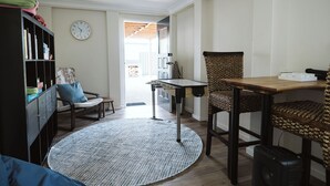 Una sala de estar con alfombra redonda, una mesa de comedor, una estantería y una silla.