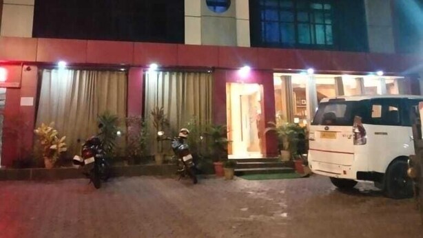 A multi-story building with a red and beige facade, multiple windows, and a well-lit entrance. - New Amr Grand (Port Blair)