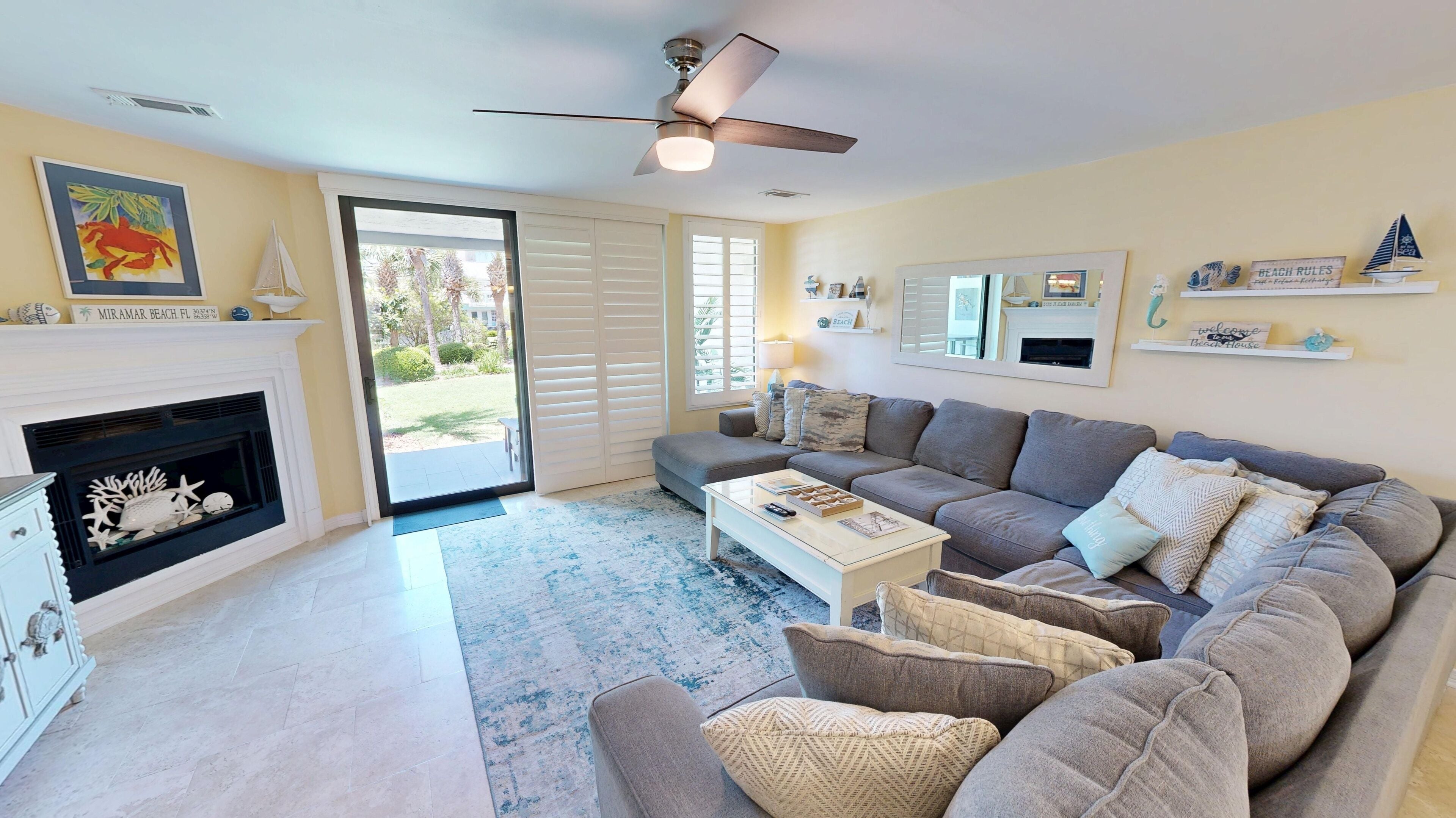 A living room with a fireplace, a sofa, a coffee table, and a ceiling fan.