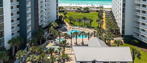 A resort with a pool area, palm trees, and a beach view.