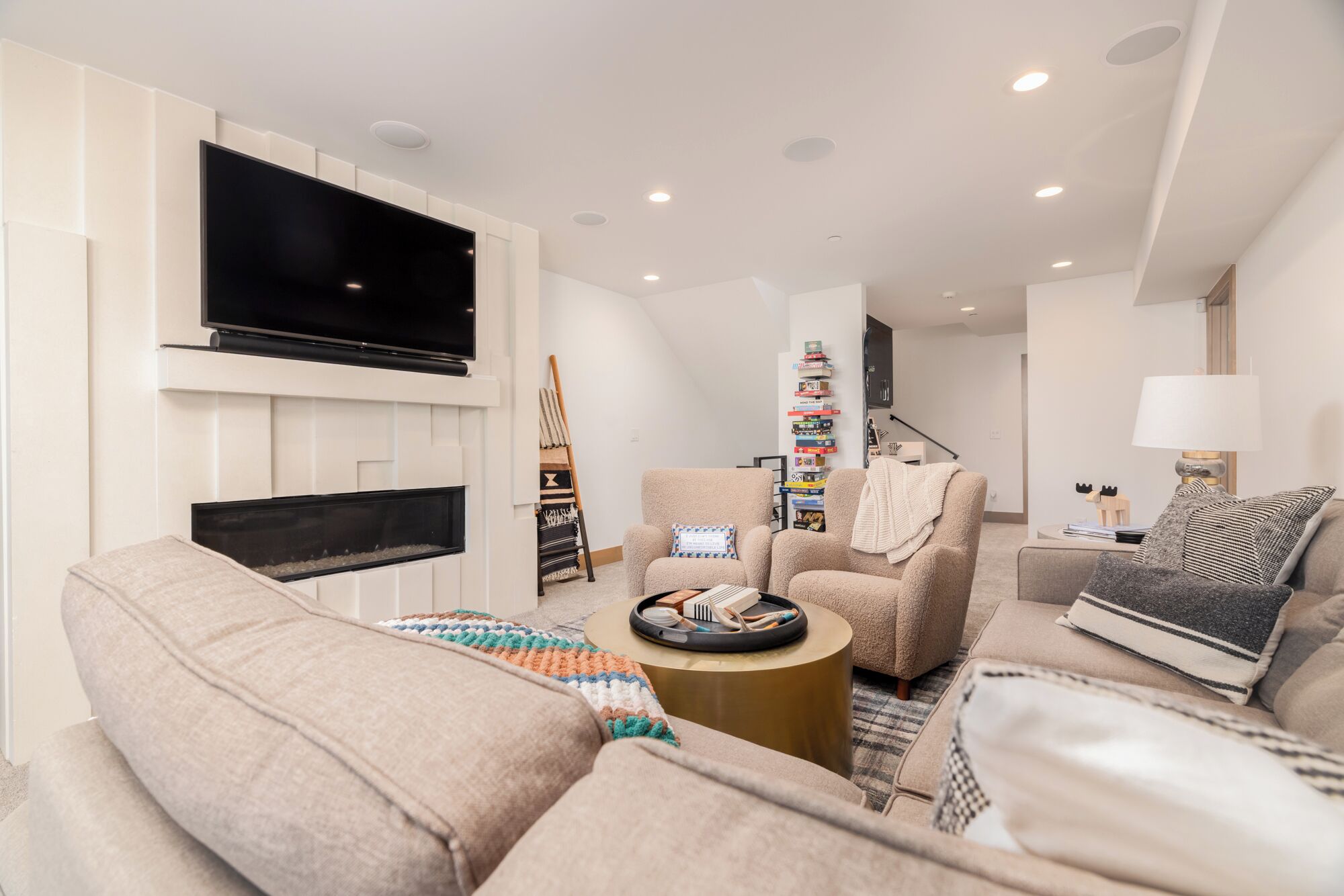 A modern living room with a flat-screen TV, a fireplace, a bookshelf, and a cozy seating area.