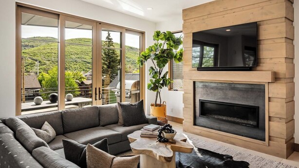 A modern living room with a large gray sectional sofa, a wooden coffee table, and a fireplace. - New Remodel Old Town House by InvitedHome | Walk to Town, Ski, Hot Tub, Patio (Park City)