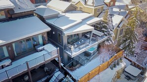 A modern multi-story residential building with a covered outdoor area, a pool, and a wooden fence. - New Remodel Old Town House by InvitedHome | Walk to Town, Ski, Hot Tub, Patio (Park City)