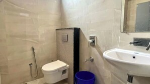 Une salle de bain moderne équipée de toilettes, d’une douche, d’un lavabo et d’un seau bleu.
