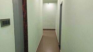 Un couloir avec une porte à gauche, une grille d’aération sur le mur et une porte à droite.