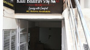 L’entrée d’un hôtel, avec une enseigne indiquant « Kaal Bhairav Stay Inn » et « Chambres de luxe avec climatisation, pour un séjour confortable ».