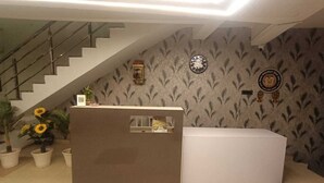 Un comptoir d’accueil avec un escalier, un papier peint à motifs et une horloge au mur.