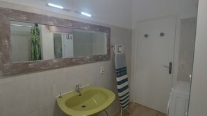 A bathroom with a large mirror, a green sink, and a striped towel hanging on a rack. - Country apartment close to the forest. You can go for a nice walk, (Boussens)