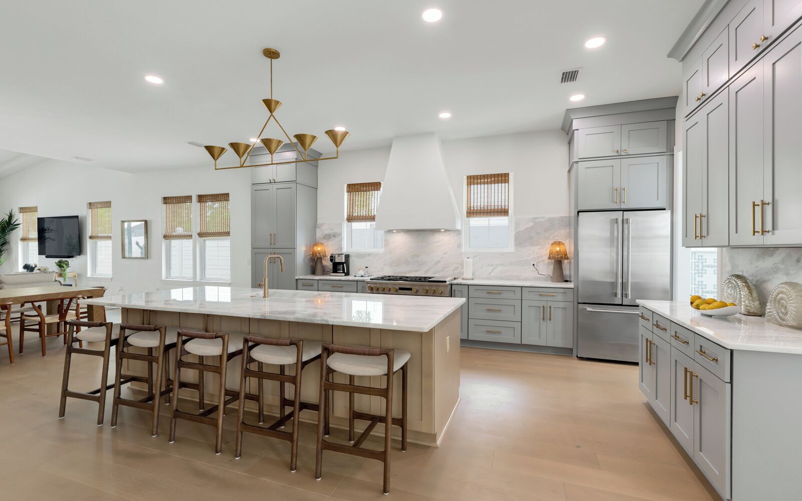 A modern kitchen with a large island, bar stools, and stainless steel appliances.
