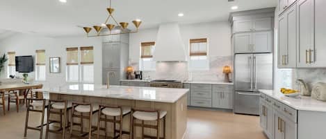 Una cocina moderna con una isla grande, taburetes de bar y electrodomésticos de acero inoxidable.