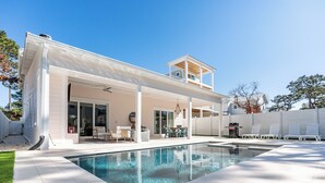 A modern two-story house with a large outdoor swimming pool, covered patio, and a separate upper deck area.