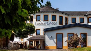 Ένα διώροφο κτίριο με την επιγραφή «Landhotel Eifelblick», η οποία υποδεικνύει ότι πρόκειται για ξενοδοχείο.