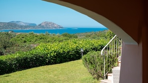 Ein Balkon mit Blick auf eine Küstenlandschaft, darunter ein Berg und das Meer.