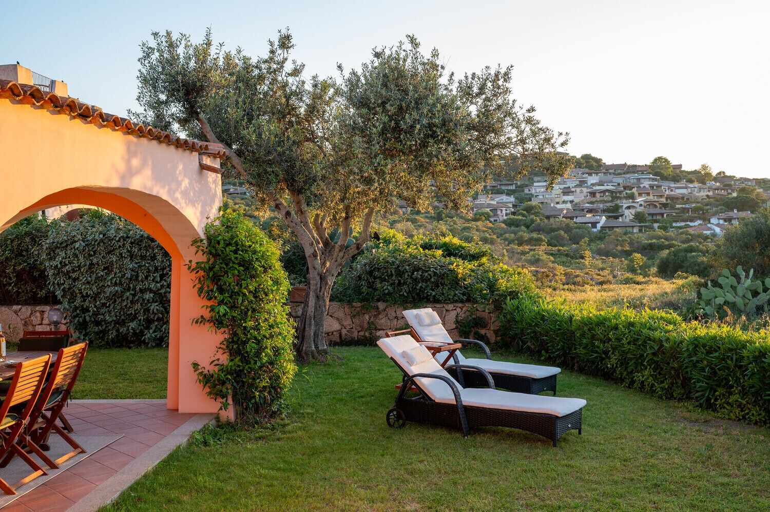 A patio with outdoor furniture, a stone archway, and a view of a residential area.