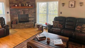 Una sala de estar acogedora con chimenea de piedra, sofás de cuero y una mesa de centro de madera.