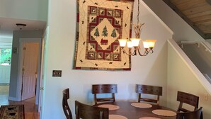Un comedor con una mesa y sillas de madera, un colcha colgante y una araña.