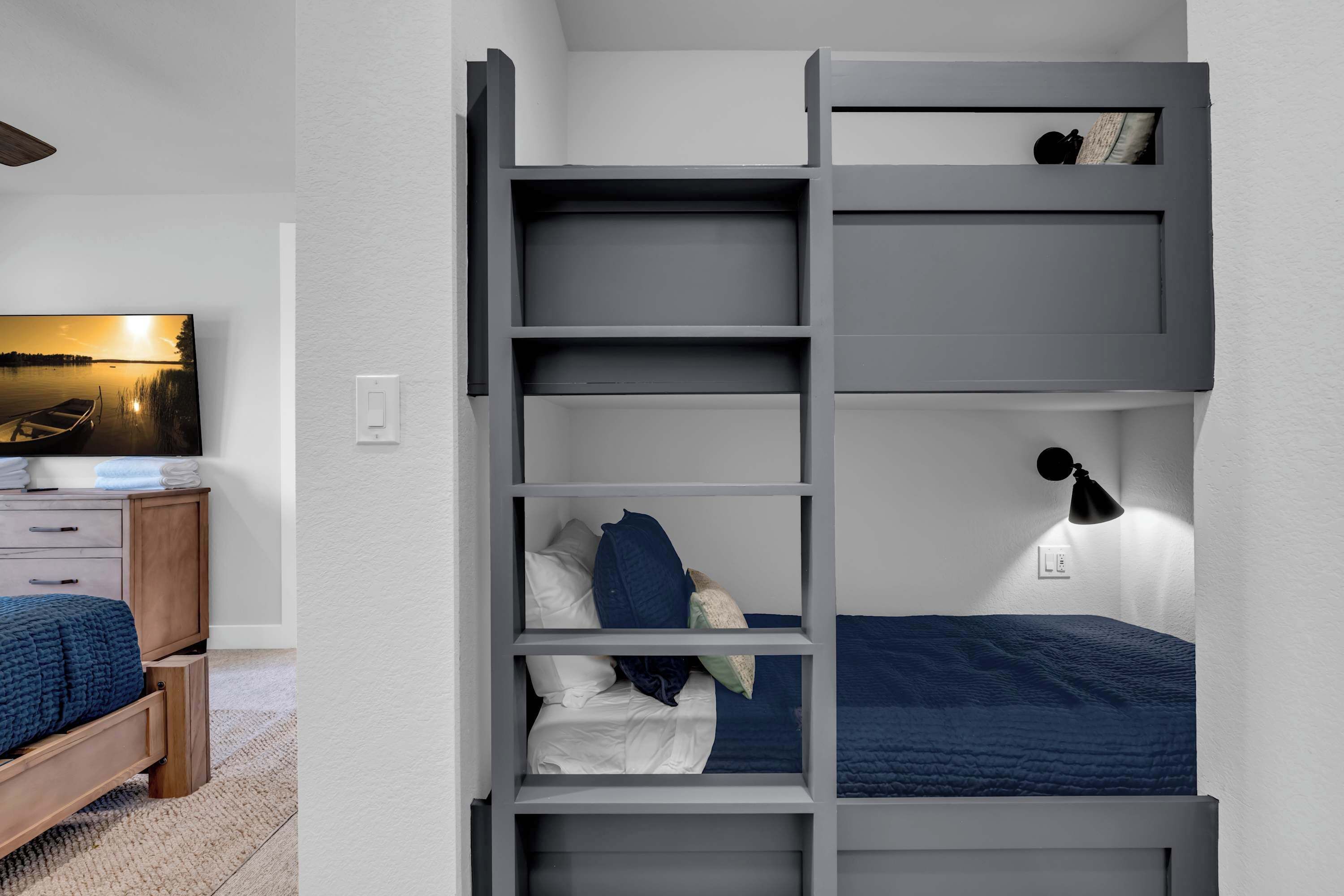 A bunk bed with a desk and a television in a bedroom.