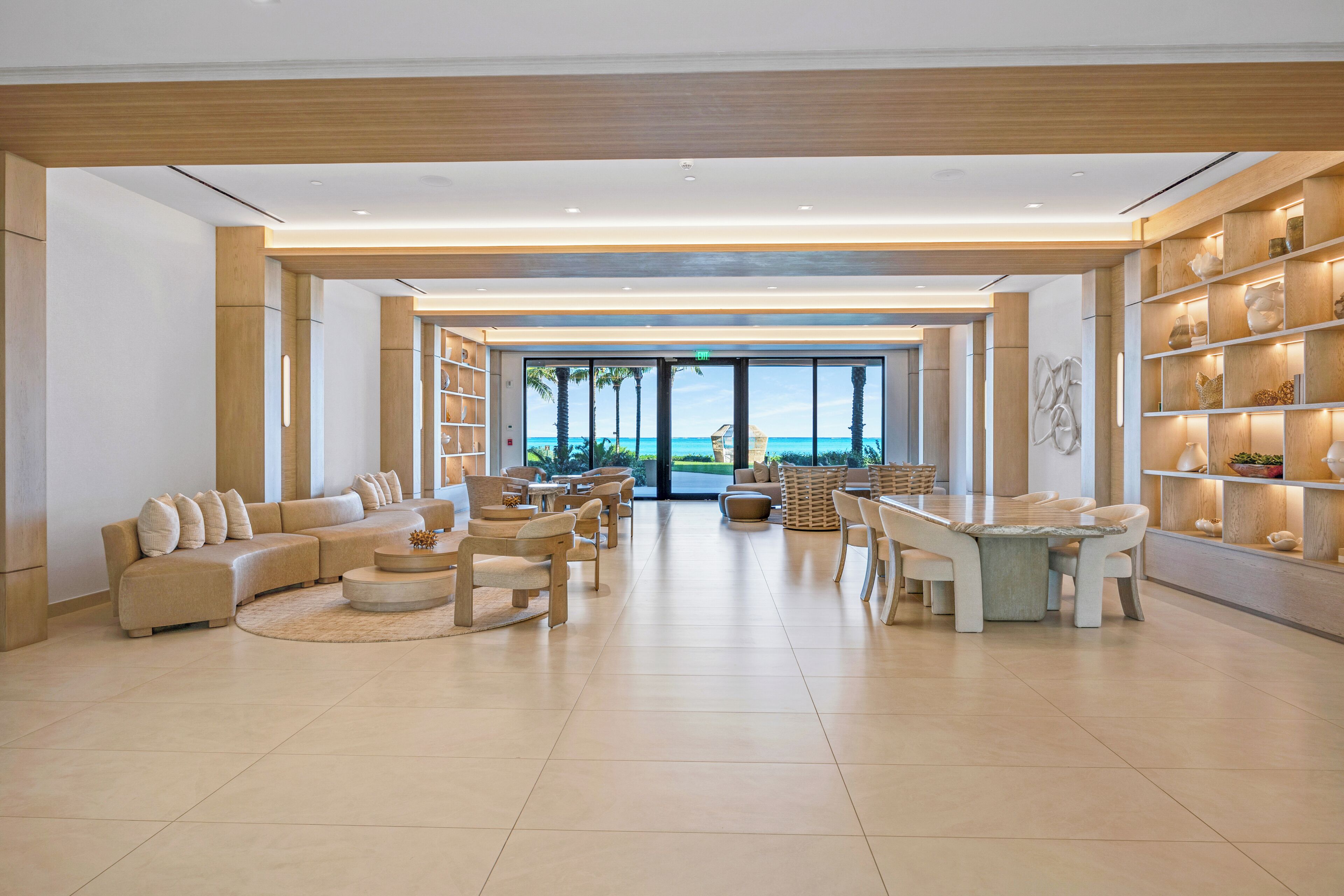 A spacious lobby with a large seating area, a reception desk, and a view of the beach.