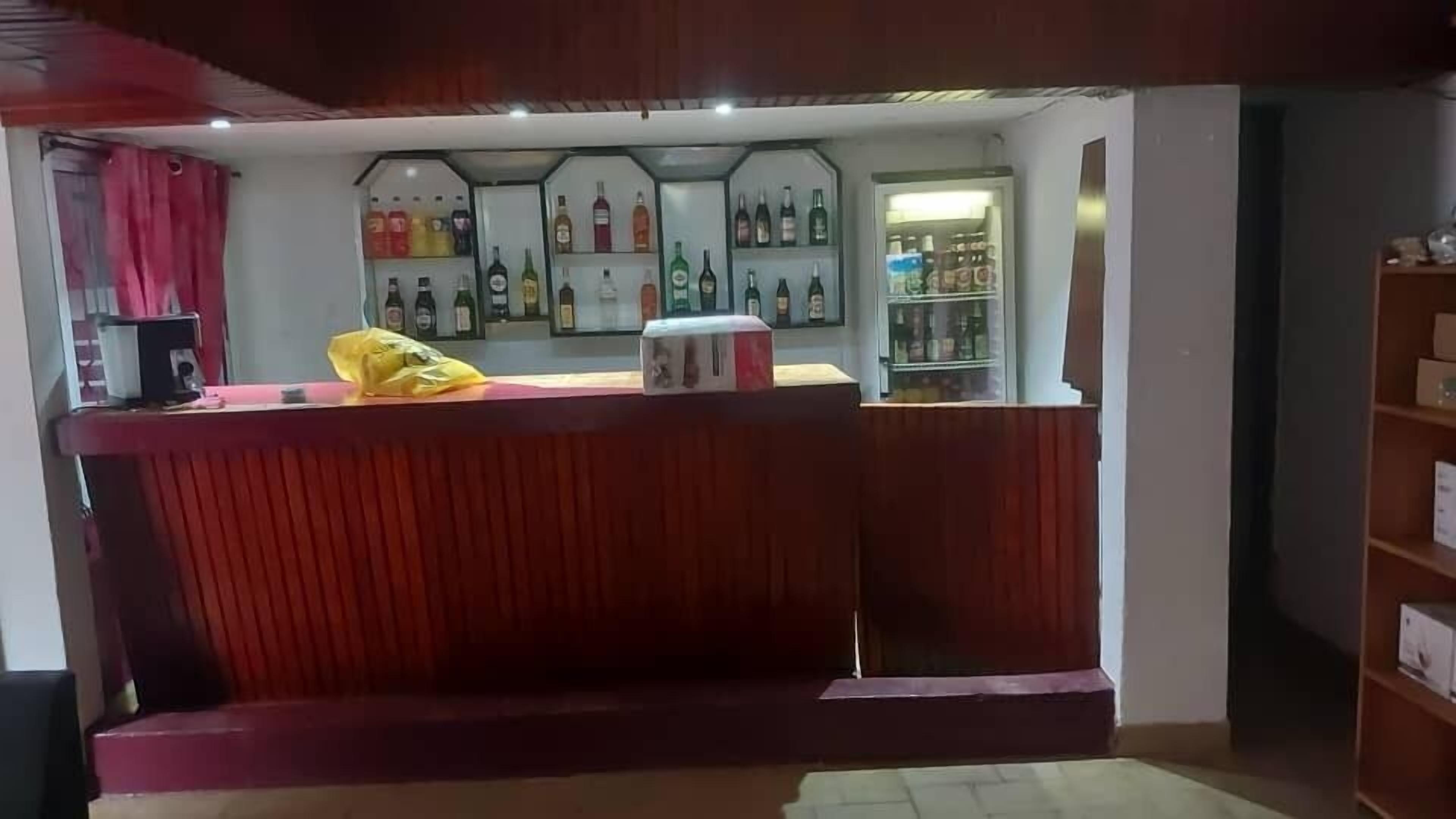 Un'area bar con un bancone, scaffali pieni di bottiglie e un frigorifero.