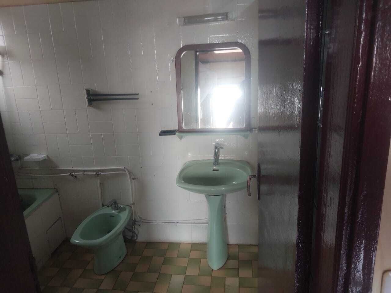 A small bathroom with a bidet, a sink, and a mirror.