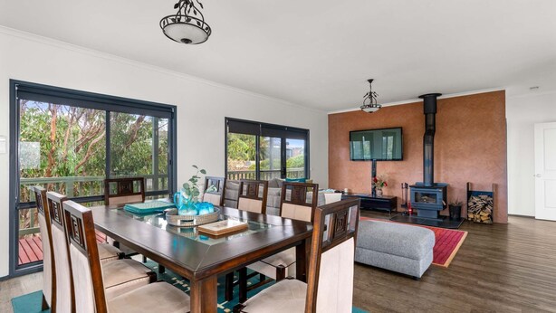 A spacious living area with a large wooden table, comfortable seating, a fireplace, and a television mounted on the wall.