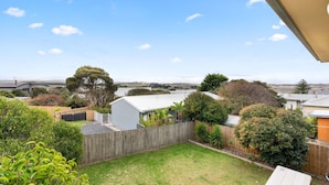 A residential backyard with a wooden fence, a shed, and a lawn.