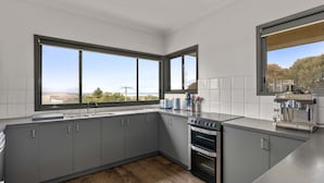 A modern kitchen with grey cabinets, a stainless steel range, and a coffee machine.