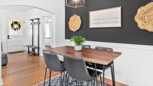 Un comedor con mesa de madera, sillas negras y lámpara colgante.