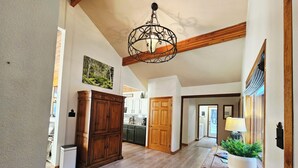 A spacious hallway with wooden flooring, a large wooden cabinet, a dining area with a table and chairs, and a kitchen in the background. - Welcome to Cozy Doo's Casa -A Warm, Woodsy Getaway in Angel Fire, NM (Angel Fire)