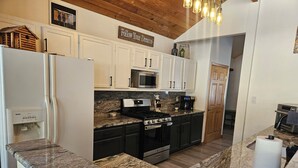 A modern kitchen with white cabinets, a stainless steel refrigerator, a microwave, a stove, and a coffee maker. - Welcome to Cozy Doo's Casa -A Warm, Woodsy Getaway in Angel Fire, NM (Angel Fire)