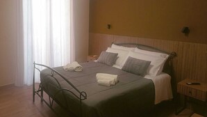 Ett hotellrum med en säng, ett nattduksbord, en luftkonditioneringsanläggning och ett fönster med gardiner.