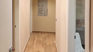 En hall med trägolv, beige väggar och ett tak med infälld belysning.