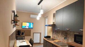 Ett modernt kök med en matplats, en TV som är monterad på väggen och en inbyggd ugn.