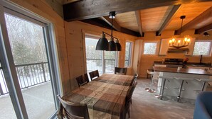 Un comedor amplio con una mesa y sillas grandes, una cocina con barra y ventanas que ofrecen vistas al exterior.