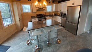 Una cocina moderna con una isla central, electrodomésticos de acero inoxidable y techo de madera.
