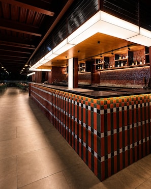A bar area with a tiled counter, shelves with bottles, and a ceiling with exposed beams. - Sleepover (Bengaluru)