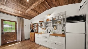 Une cuisine avec des meubles blancs, un plan de travail en bois, un réfrigérateur blanc et un four à micro-ondes.