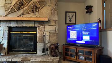 A living room with a stone fireplace, a television, and a wooden cabinet.