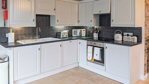Una cocina moderna con armarios blancos, encimera negra y salpicadero de azulejos.