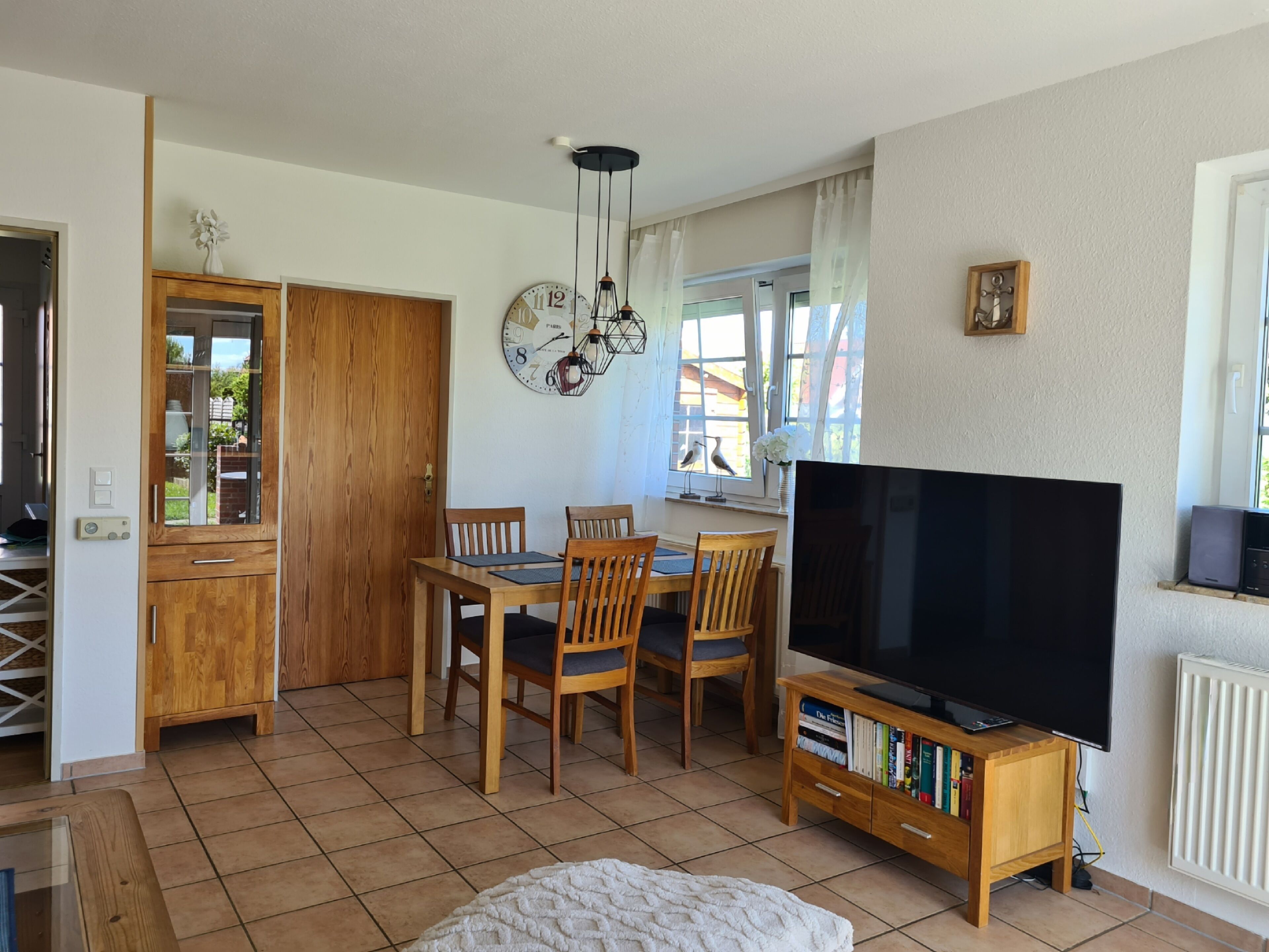 Un comedor con una mesa y sillas de madera, un televisor de pantalla plana grande y una estantería.