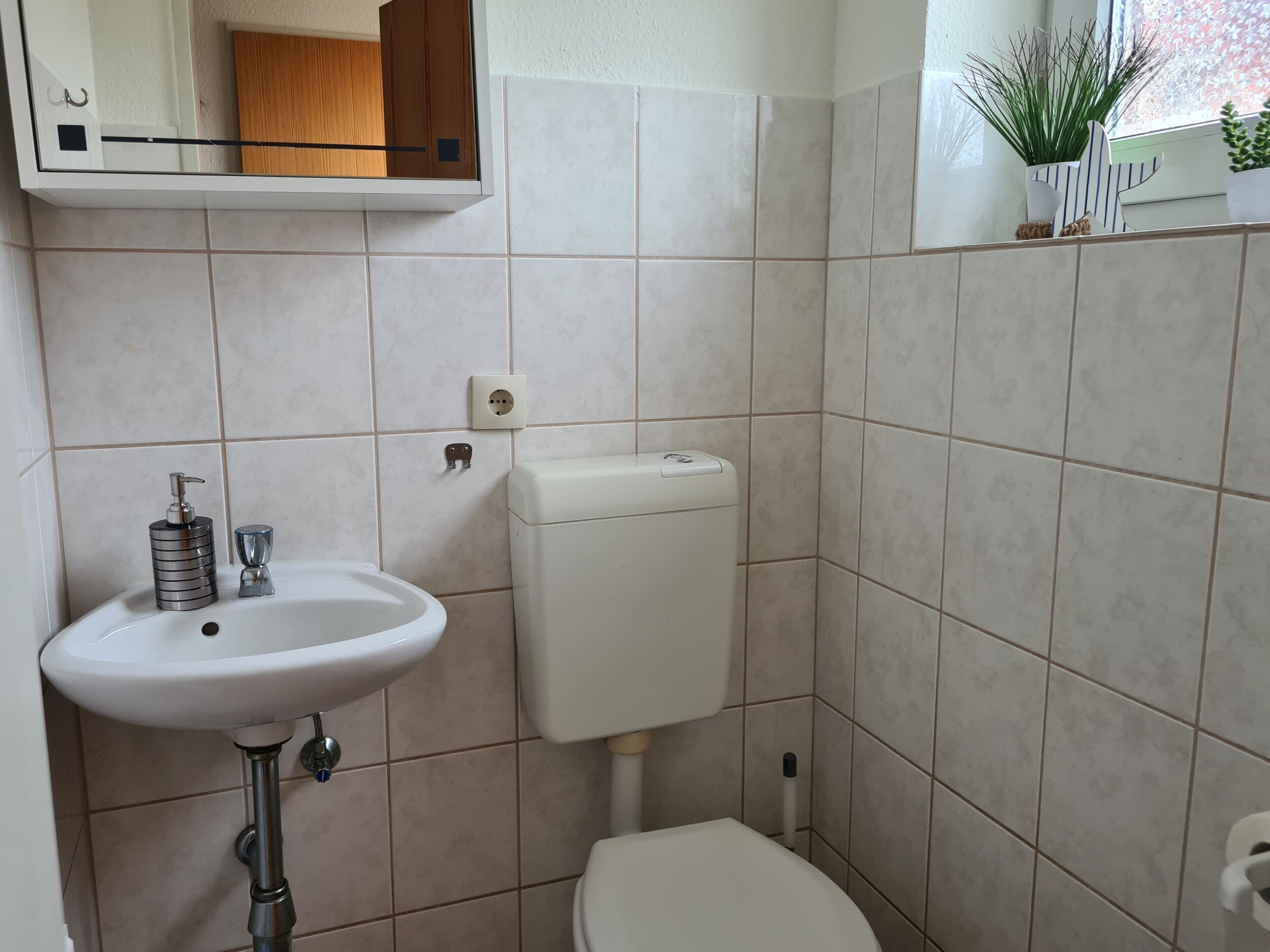 Un baño con un lavabo blanco, inodoro y un espejo sobre el lavabo.
