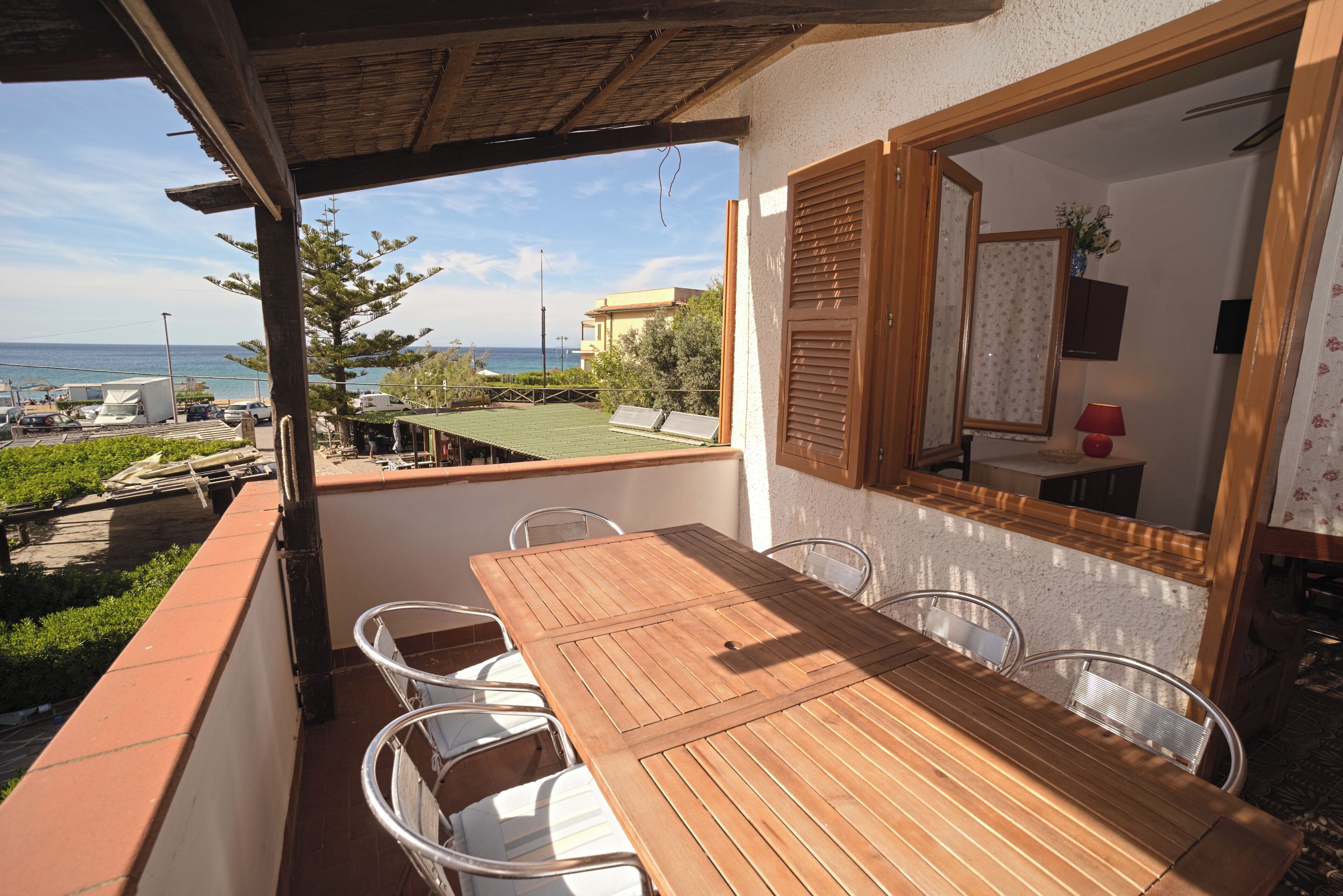 Ein Holztisch mit Stühlen auf einem Balkon mit Blick auf das Meer und Gebäude.